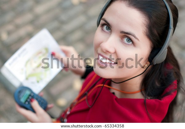 Young\
woman with headphones, listening to audio\
guide