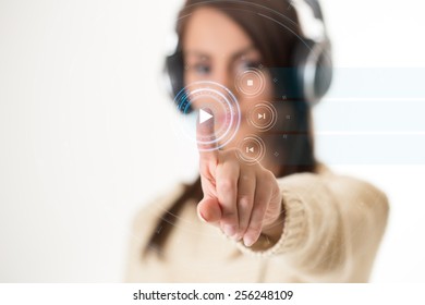 Young woman in headphones pushing virtual button on touch screen. - Shutterstock ID 256248109