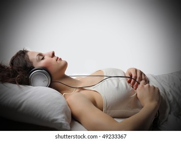 Young Woman With Headphones Relaxing On A Bed