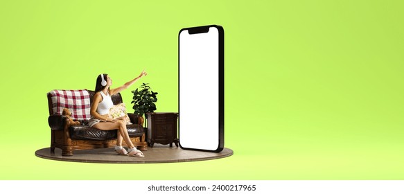 Young woman in headphones sitting on couch near giant 3D model of mobile phone with empty screen over green background. Online services, business, e-commerce. Mockup for text, ad, design, logo - Powered by Shutterstock