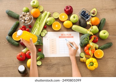 Young woman with healthy food making meal plan on wooden table, top view. Diet concept - Powered by Shutterstock