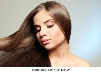 Young woman with healthy hair on light background - Shutterstock ID 484405429