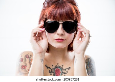 Young Woman With Heart Shaped Tattoo In Chest Wearing Sunglassess Staring Into Camera Seriously