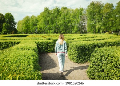 Young Woman In Hedge Maze On Sunny Day, Back View