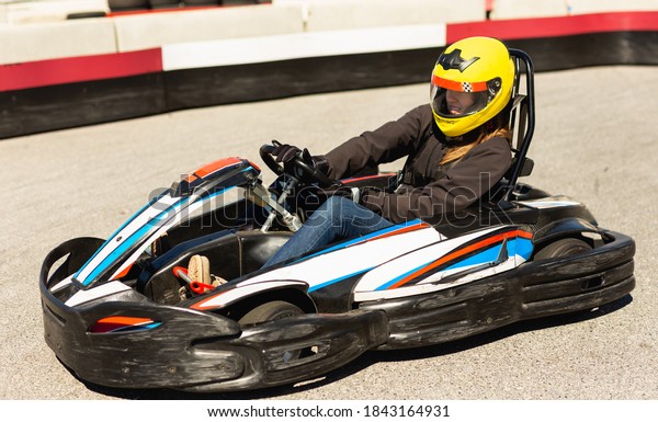 Young woman in helmet driving car for karting in\
sport club outdoor