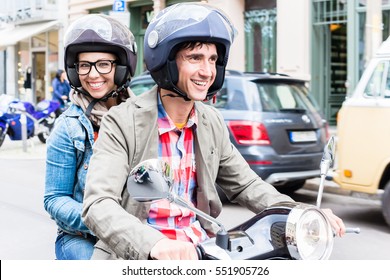 Young Woman With Helmet Sitting On Pillion Seat Of Vespa In Streets Of Berlin