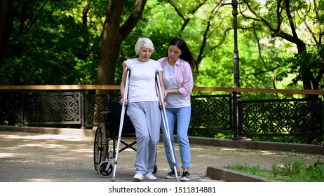 Young Woman Helping Old Lady Walking On Crutches, Hip Fracture Rehabilitation