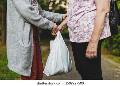 Young Woman Helping Senior With Bag In The Park On A Sunny Day - Female Caring For Elderly Prople - Beautiful And Respectful Gestuure Made For The Others