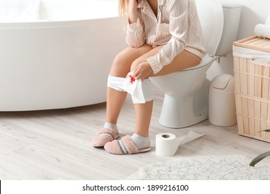 Young Woman With Hemorrhoids Sitting On Toilet Bowl At Home