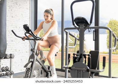 Young woman in her 20s using a stationary bike at the gym. Sport and health concept - Powered by Shutterstock