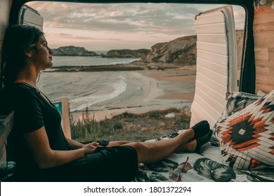 Young woman in her camper observing a good view of a beach