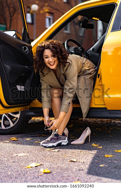 young woman in her car, a world of strong,\
successful women. Woman at the wheel changes clothes, shoes on\
stilettos changes for\
sneakers