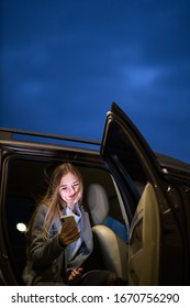 Young Woman With Her Cell Phone Sitting In The Backseat Of A Car, Getting Ready To Travel (color Toned Image; Shallow DOF)