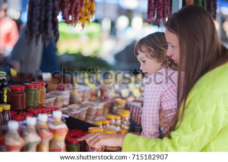 Young woman and her daughter at the bazaar, buying food ingridients