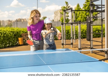Young woman with her daughter playing ping pong in park