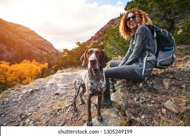 A Young Woman And Her Dog Hiking To The Top Of A Mountain