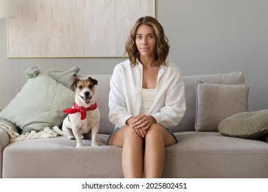 Young Woman And Her Dog On Sofa At Home. Adorable Pet.