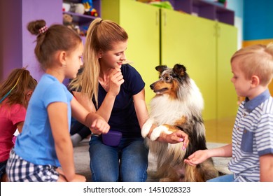 Young Woman And Her Dog Playing With Children During Therapy