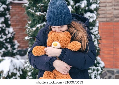 Young woman with her favorite teddy bear in her arms in winter.