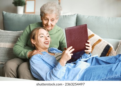 Young woman and her grandmother with photo album at home - Powered by Shutterstock