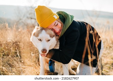 Young Woman And Her Husky Dog Trek Down A Forest Trail Offering A Scenic View Of The Trees Changing Colors. Fit Girl Takes Her Miniature Pinscher For A Walk In Woods