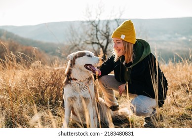 Young Woman And Her Husky Dog Trek Down A Forest Trail Offering A Scenic View Of The Trees Changing Colors. Fit Girl Takes Her Miniature Pinscher For A Walk In Woods