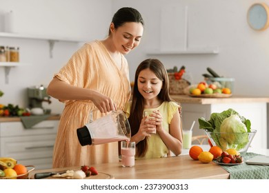 Young woman with her little daughter pouring fresh smoothie into glass in kitchen - Powered by Shutterstock