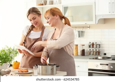 Young Woman And Her Mother Cooking In Kitchen