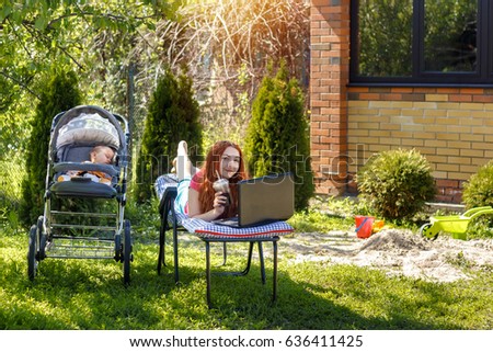 Young woman with her newborn baby lying on the grass in the park and enjoying sunny summer day. Mother with child outdoors. Motherhood.