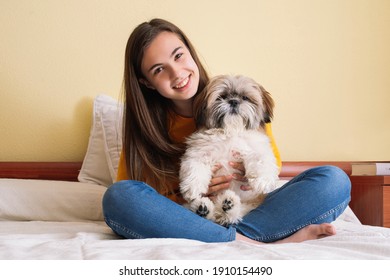 Young Woman With Her Pet Dog Playing On The Bed