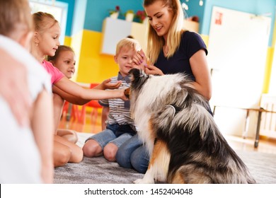 Young Woman And Her Therapy Dog Working With Children 