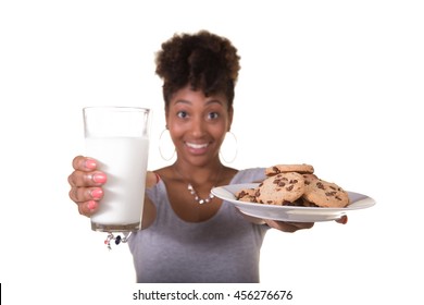 Young Woman In Her Twenties Holding A Glass Of Milk And A Plate Of Cookies
