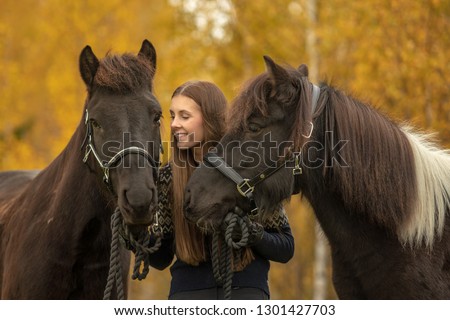 Young woman with her two best friends. Her Icelandic horses with a yellow autumn background