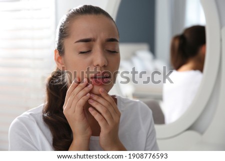 Young woman with herpes on lip at home