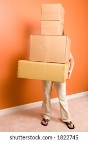 Young Woman Hidden Behind The Tall Stack Of Boxes She Is Carrying. Concept Is Moving Into A New Home Or College Dorm.