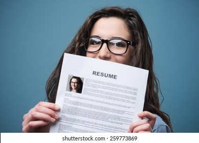 Young woman hiding behind her resume - Shutterstock ID 259773869
