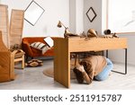 Young woman hiding under table during earthquake in office