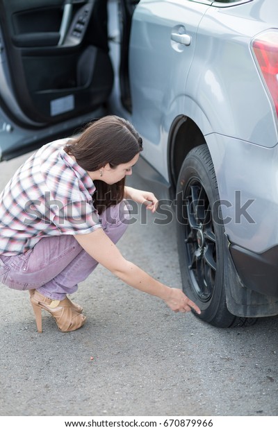Young woman with high heels in the city with\
flat tire, frustrated near broken\
car