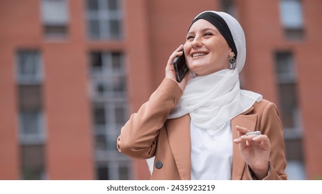 Young woman in hijab talking on smartphone outdoors.  - Powered by Shutterstock