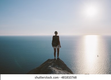 Young woman hiker with backpack standing on cliff and looking forward on the background of the sea, sky. lady tourist on top of a mountain enjoying view.  - Shutterstock ID 481810768