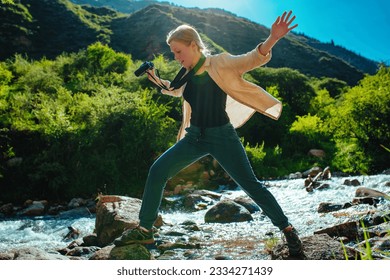 Young woman hiker crossing mountain stream at sunny day - Powered by Shutterstock