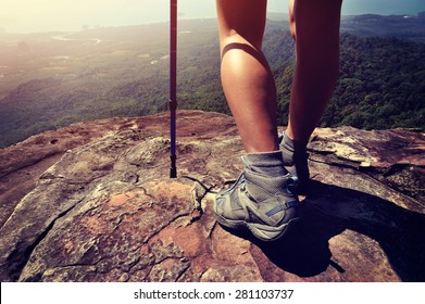 young woman hiker legs on mountain peak cliff