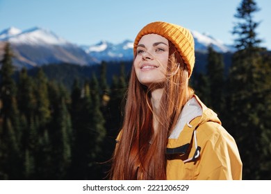 Young Woman Hiker Portrait In Yellow Raincoat Looking Into Camera And Smiling With Teeth Traveling And Hiking In The Mountains In The Sunset