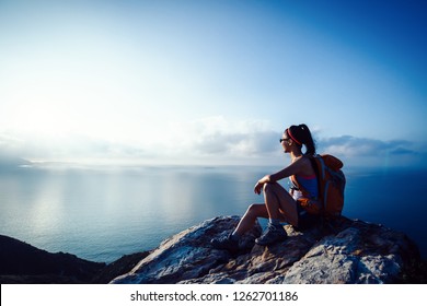 Young woman hiker at sunrise seaside mountain peak