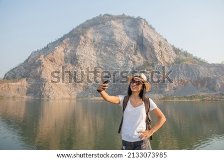 young woman hiker use smart phone taking photo on mountain peak travel and active lifestyle. Hipster girl with backpack hold on smart phone gadget. Summer vacations concept.