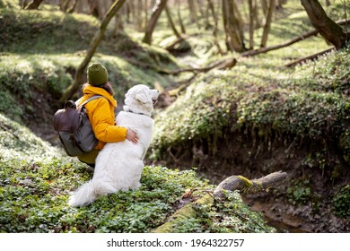 Young Woman In Hiking Clothes And Backpack Sitting Near Big White Dog In Green Spring Forest. Enjoys And Explore Of Tranquil Nature.