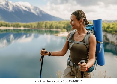 A young woman is hiking joyfully near beautiful mountains alongside a serene lake - Powered by Shutterstock