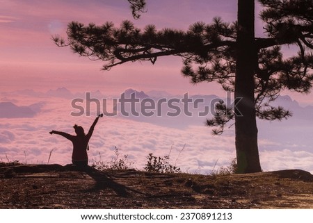 Young woman hiking on the cliff and sea of mist, Phu Kradueng national park, Loei province, Thailand.