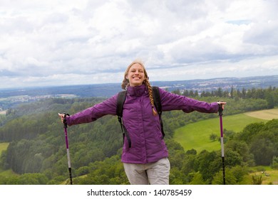 Young woman with hiking sticks top of the mountain