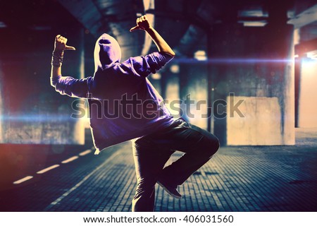 Young woman hip-hop dancer on urban background with flare effects